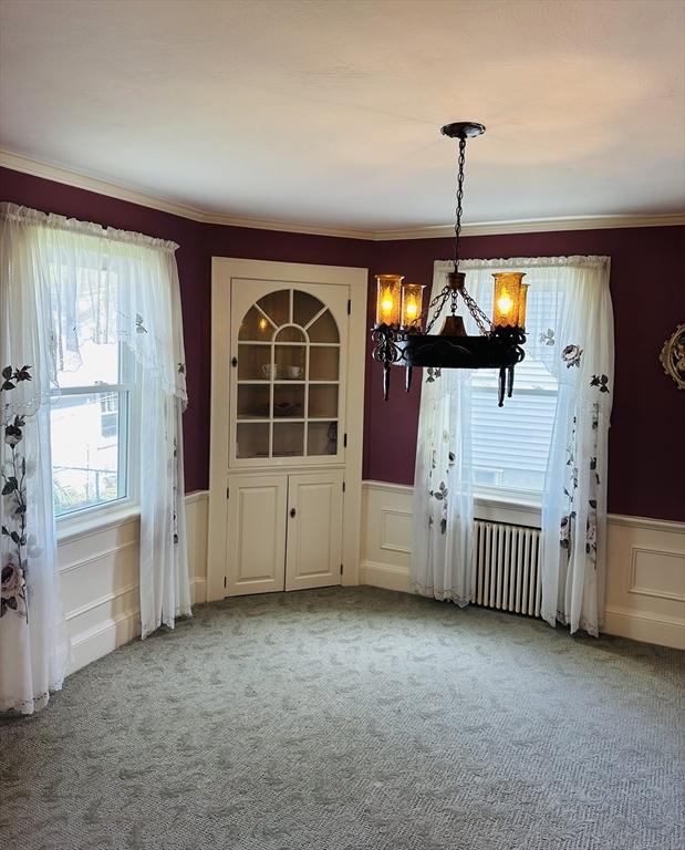 70 Sherman St, Quincy, MA 02170 - unfurnished dining area with a wainscoted wall, carpet floors, a chandelier, a decorative wall, and crown molding