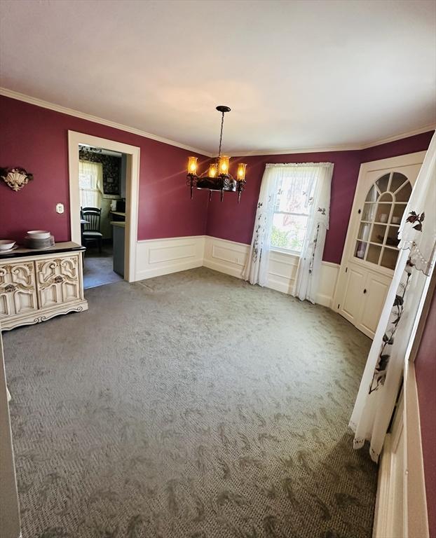 70 Sherman St, Quincy, MA 02170 - unfurnished dining area featuring ornamental molding, a chandelier, carpet floors, wainscoting, and a decorative wall