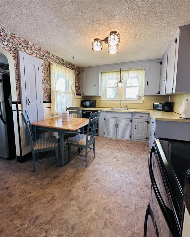 70 Sherman St, Quincy, MA 02170 - kitchen featuring plenty of natural light, black appliances, a sink, a textured ceiling, and light countertops