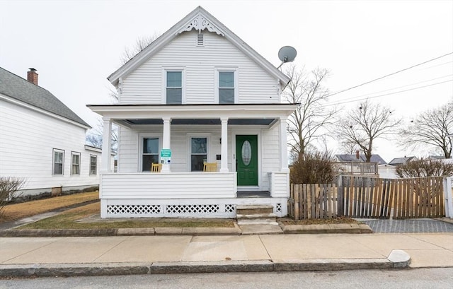 view of front of home with a porch and fence