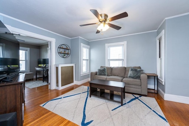 living area with crown molding, wood finished floors, and baseboards