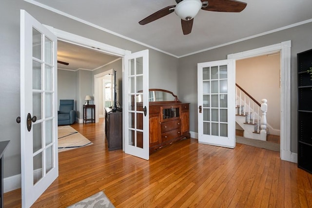 empty room featuring french doors, crown molding, a ceiling fan, and hardwood / wood-style floors