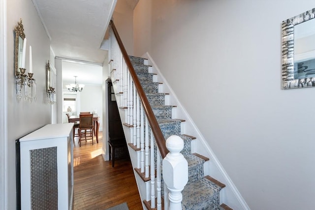 staircase featuring a chandelier and wood finished floors