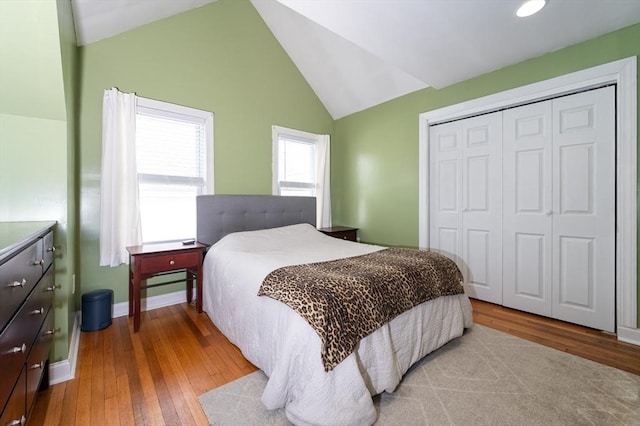 bedroom featuring a closet, baseboards, lofted ceiling, and hardwood / wood-style flooring