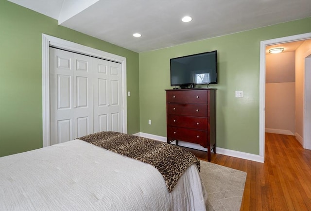 bedroom with a closet, recessed lighting, baseboards, and wood finished floors