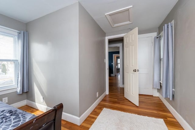 bedroom featuring attic access, light wood-type flooring, and baseboards