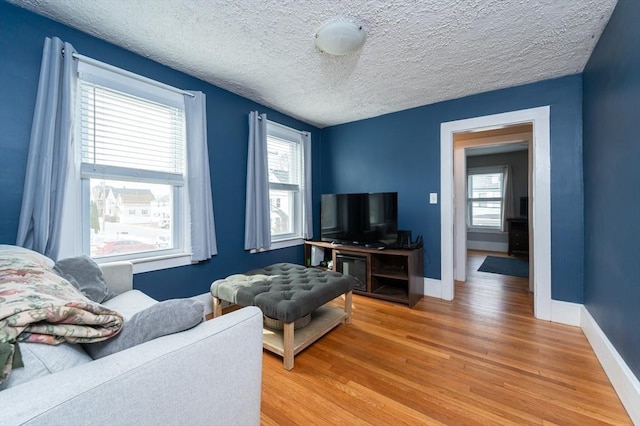 living area featuring light wood-style floors, baseboards, and a textured ceiling