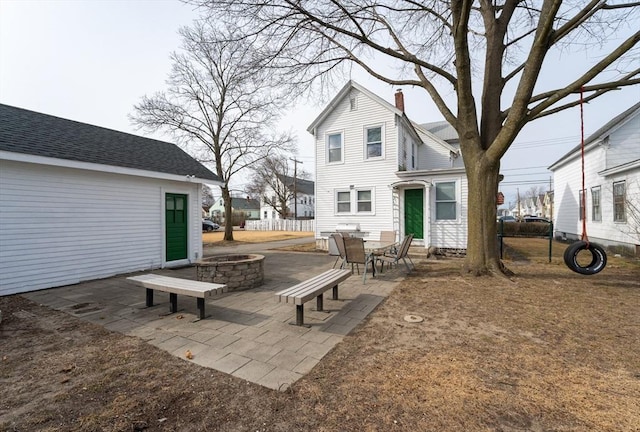 rear view of property with a chimney, entry steps, an outdoor fire pit, and a patio