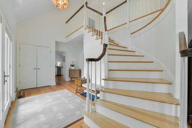 stairway with a towering ceiling and wood finished floors