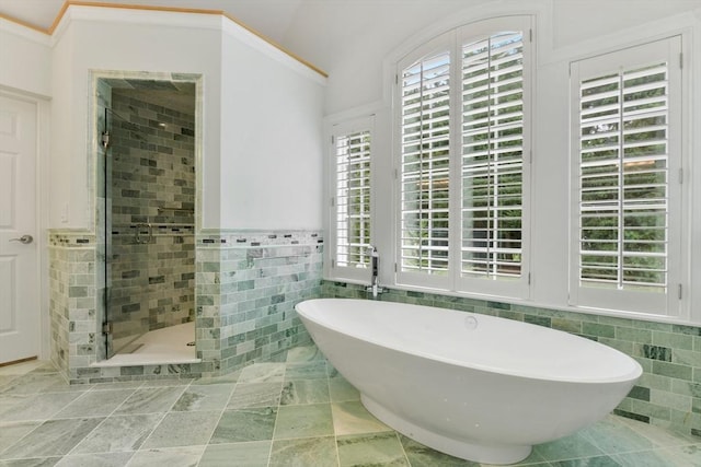 bathroom featuring tile walls, a freestanding tub, wainscoting, and a shower stall