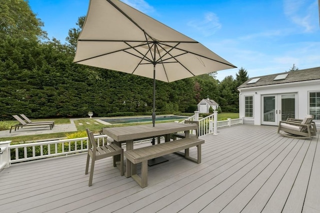 wooden terrace with an outbuilding, french doors, an outdoor pool, a shed, and outdoor dining space