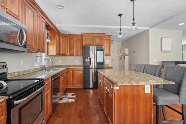 kitchen with dark wood-style flooring, brown cabinets, a breakfast bar area, appliances with stainless steel finishes, and a sink