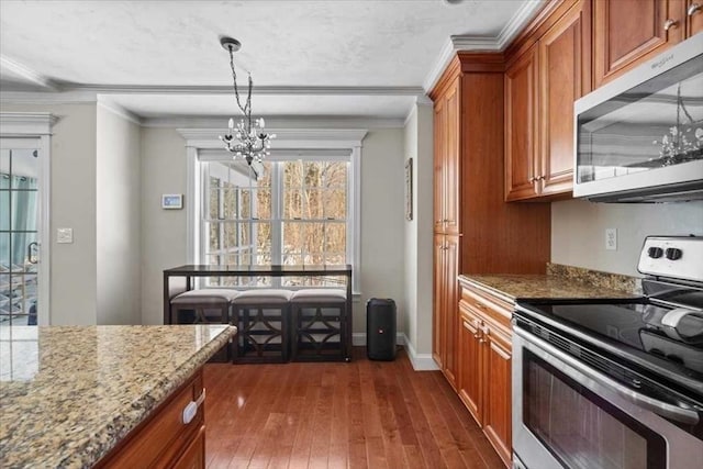 kitchen with ornamental molding, appliances with stainless steel finishes, brown cabinets, and an inviting chandelier