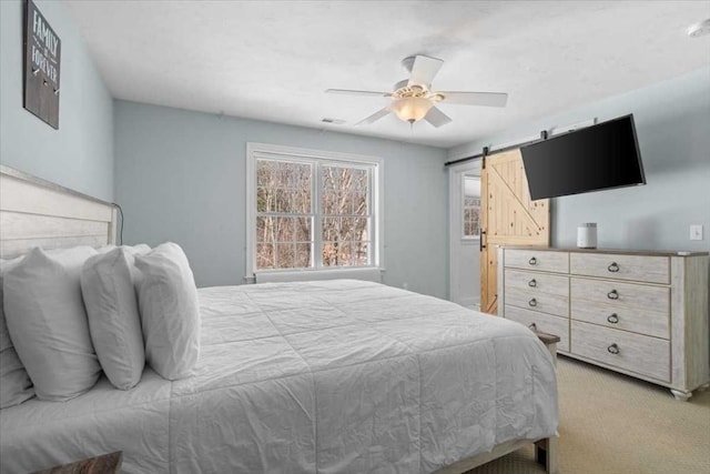 carpeted bedroom featuring ceiling fan, a barn door, and visible vents