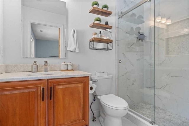 bathroom with toilet, a marble finish shower, and vanity