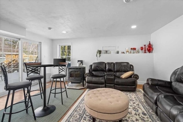 living room featuring light wood-type flooring, a wood stove, and baseboards