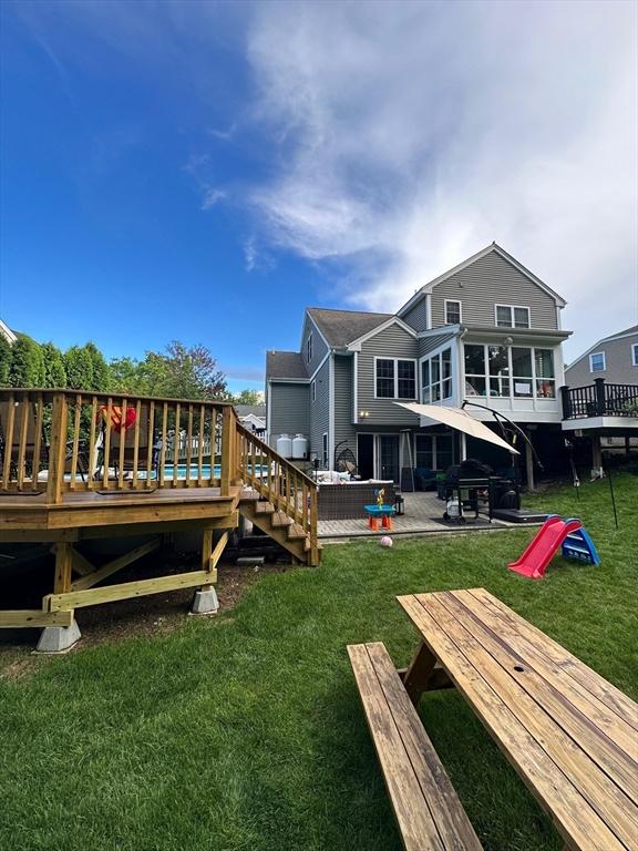 back of property with a yard and a wooden deck