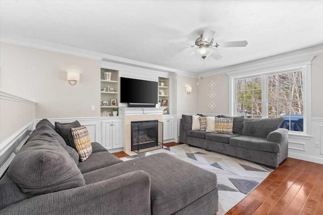 living room with light wood finished floors, a decorative wall, a tiled fireplace, and crown molding