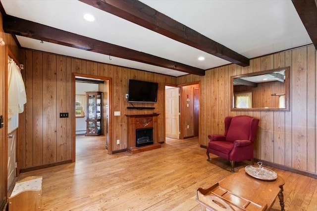 72 Heath St, Tewksbury, MA 01876 - living room with light wood-style flooring, beamed ceiling, baseboard heating, a fireplace with raised hearth, and wood walls