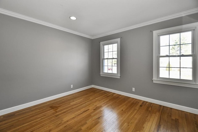 empty room featuring wood-type flooring, baseboards, and ornamental molding