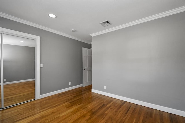 unfurnished room with visible vents, baseboards, wood finished floors, and crown molding