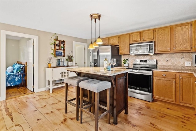 27 Lakeview St, Southwick, MA 01077 - kitchen featuring light wood-style floors, a center island, tasteful backsplash, and stainless steel appliances