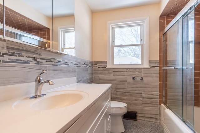 full bathroom with vanity, tile walls, shower / bath combination with glass door, and toilet