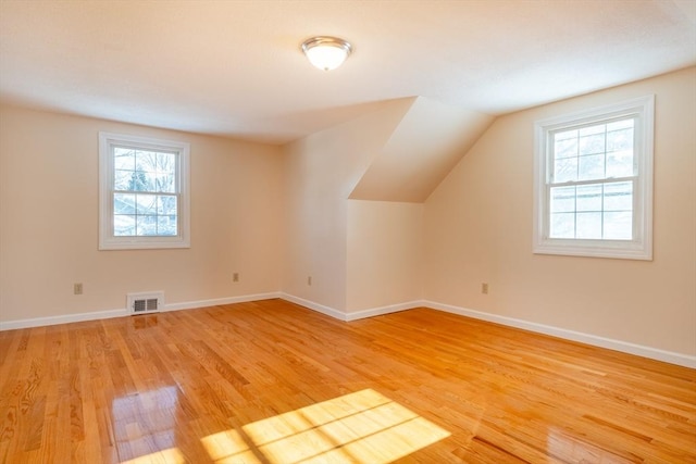 additional living space with wood-type flooring and vaulted ceiling