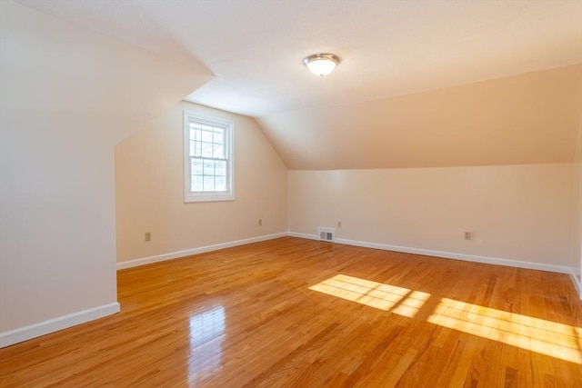 additional living space featuring vaulted ceiling and light wood-type flooring