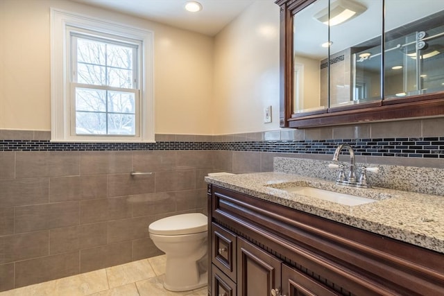 bathroom featuring vanity, tile walls, tile patterned floors, and toilet