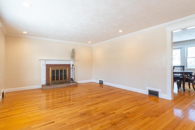 unfurnished living room featuring ornamental molding, a fireplace, and light hardwood / wood-style flooring