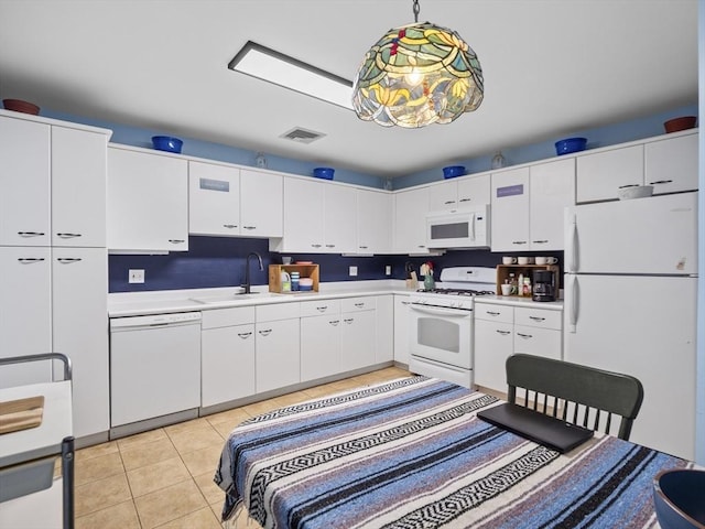 kitchen with white appliances, light tile patterned floors, sink, pendant lighting, and white cabinetry