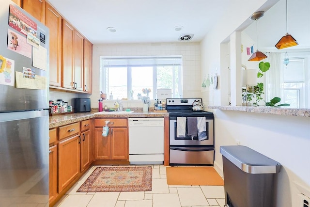 33 Saint Paul St Unit 3, Brookline, MA 02446 - kitchen featuring stainless steel appliances, brown cabinetry, light countertops, hanging light fixtures, and light tile patterned flooring