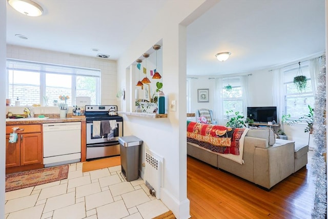 33 Saint Paul St Unit 3, Brookline, MA 02446 - kitchen featuring white dishwasher, stainless steel electric range oven, radiator, brown cabinetry, and open floor plan