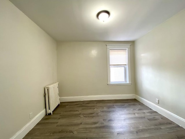 empty room featuring radiator heating unit and dark hardwood / wood-style floors