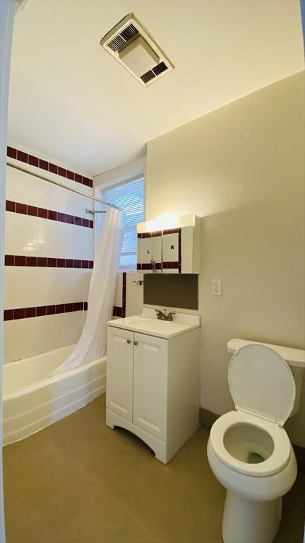 full bathroom featuring shower / bathtub combination with curtain, vanity, tile patterned flooring, and toilet