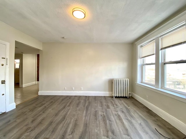 spare room with wood-type flooring, radiator, and a textured ceiling