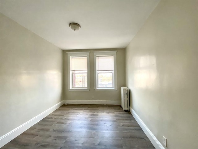 spare room featuring radiator and dark wood-type flooring