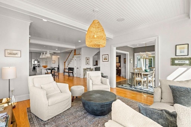 living room with ornamental molding, wood finished floors, baseboards, stairway, and a notable chandelier