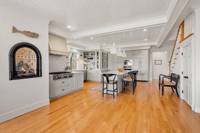 kitchen featuring crown molding, appliances with stainless steel finishes, open shelves, custom exhaust hood, and light wood finished floors