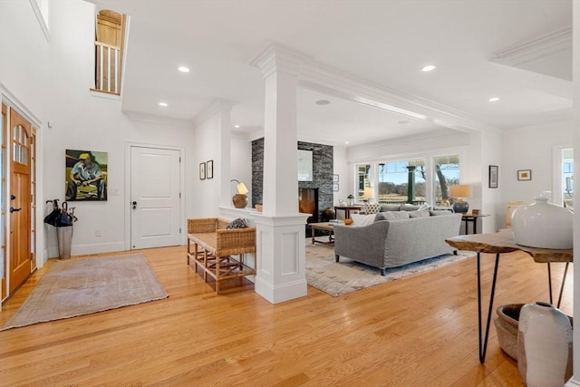 living room featuring recessed lighting, a stone fireplace, ornamental molding, and light wood-type flooring