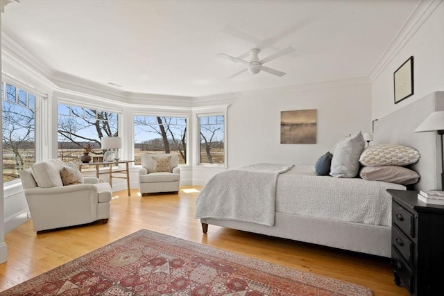 bedroom with light wood-style floors, crown molding, and multiple windows