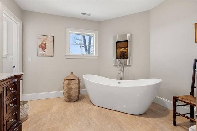 full bathroom featuring a freestanding bath, baseboards, vanity, and visible vents