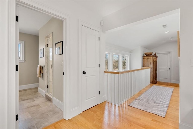 corridor featuring baseboards, visible vents, wood finished floors, and lofted ceiling