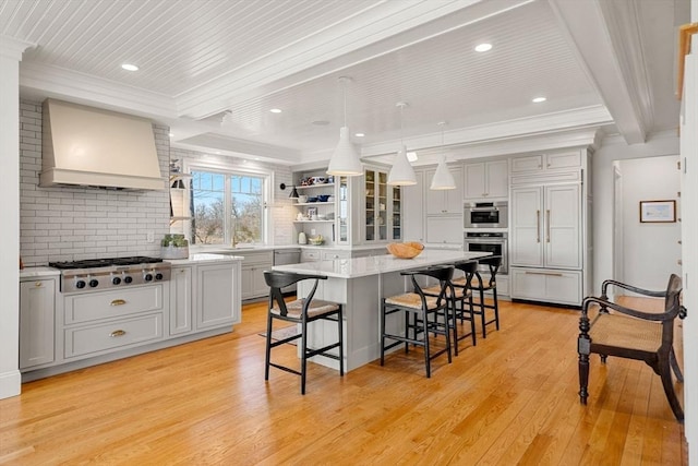 kitchen featuring a kitchen breakfast bar, a kitchen island, open shelves, premium range hood, and light wood-style flooring