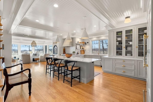 kitchen with gray cabinets, light wood-type flooring, a healthy amount of sunlight, and a kitchen bar