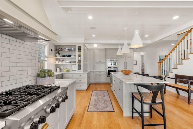 kitchen featuring a breakfast bar area, a center island, custom range hood, light stone counters, and stainless steel appliances