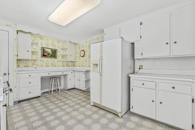 kitchen featuring white cabinetry and white refrigerator with ice dispenser