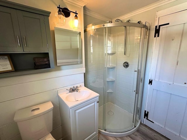 bathroom featuring toilet, ornamental molding, wood finished floors, a shower stall, and vanity