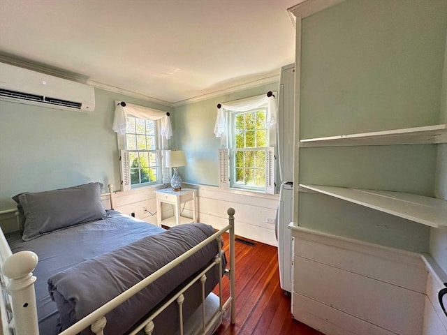 bedroom featuring a wainscoted wall, multiple windows, a wall mounted AC, and dark wood-style flooring